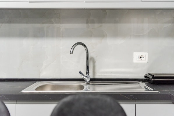 Een keuken met een RVS spoelbak, een moderne kraan en een zwart aanrecht.