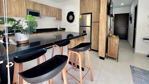 Uma cozinha moderna com armários de madeira, bancada preta e uma ilha central com banquetas.