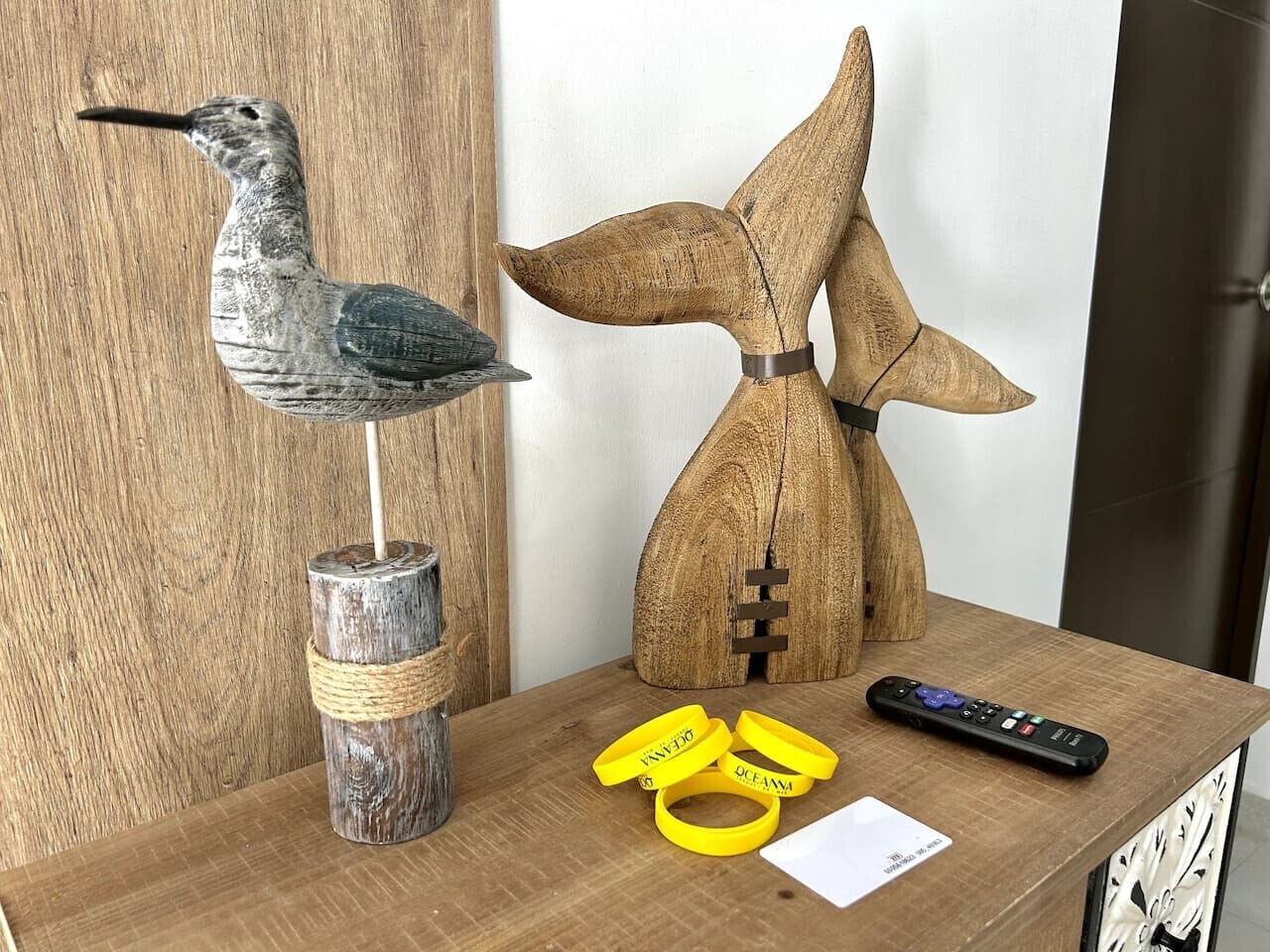 Ein Holztisch mit einer Vogelstatue, einer Hundestatue und einer Fernbedienung.