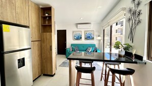 Uma cozinha moderna com geladeira embutida, armários de madeira e um espaço de refeições com mesa preta e banquetas.