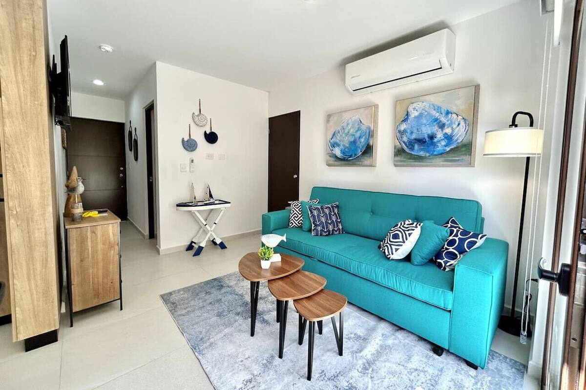 A modern living room with a teal sofa, wooden side table, and a coffee table.