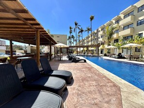 A poolside area with lounge chairs, umbrellas, and a clear blue pool. - Oceanna Apartments  (Mazatlán)