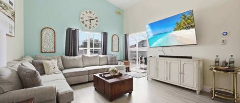 A living room with a sofa, coffee table, and a TV mounted on the wall.