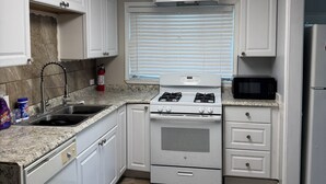 A kitchen with white cabinets, a stainless steel sink, a gas stove, a microwave, and a refrigerator. - Luxury West 7th Fort Worth Stay - Balcony • W/D (Fort Worth)