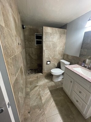 A bathroom with a shower, toilet, and vanity. - Luxury West 7th Fort Worth Stay - Balcony • W/D (Fort Worth)