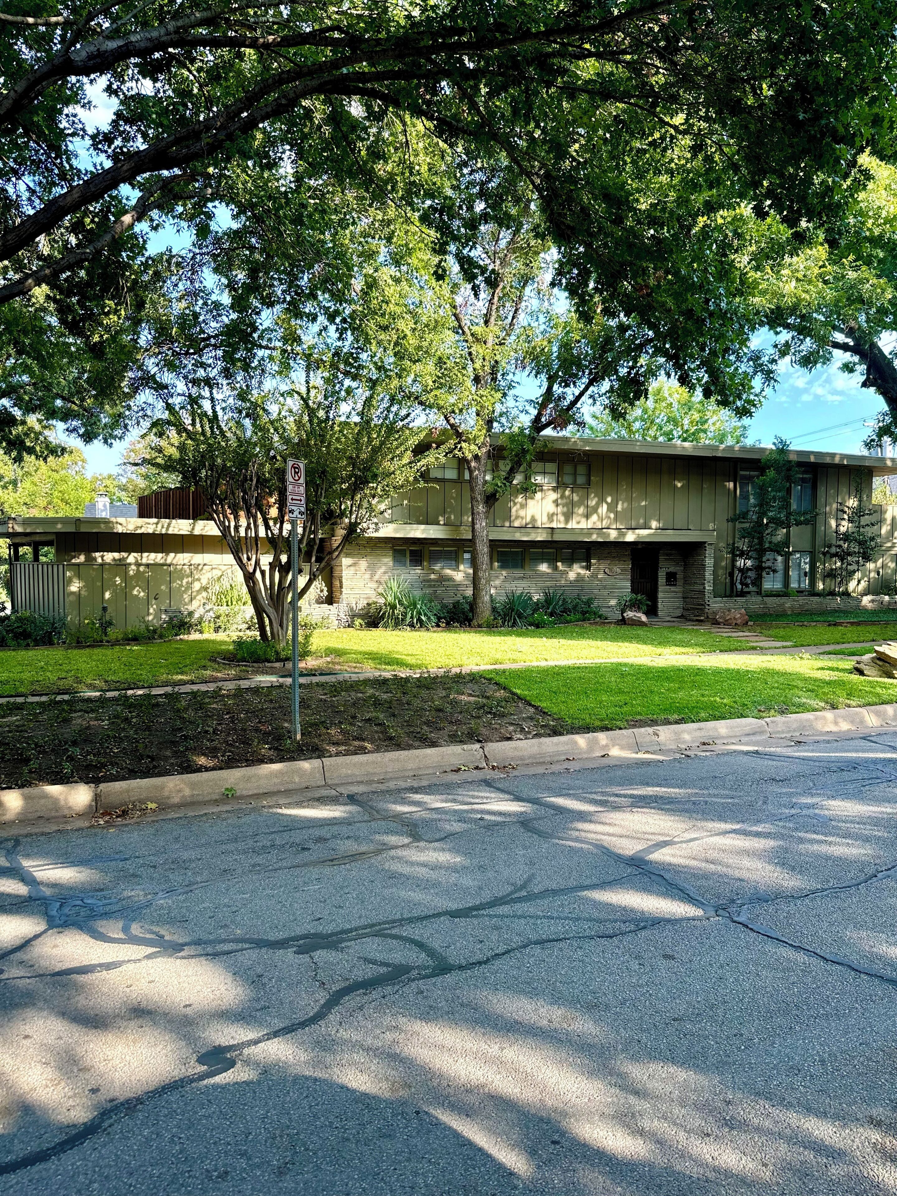 A two-story building with a flat roof, surrounded by a well-maintained lawn and trees.