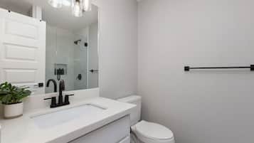 Une salle de bain moderne avec un lavabo blanc, un robinet noir et un grand miroir au-dessus.