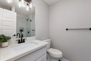 Un baño moderno con un lavamanos blanco, un grifo negro y un espejo grande encima.