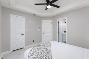 Un dormitorio con cama, ventilador de techo y puertas blancas.