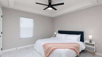 Een slaapkamer met een bed, nachtkastjes, een plafondventilator en een raam.