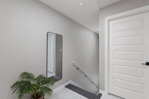 A staircase with a handrail, a white door, and a potted plant.
