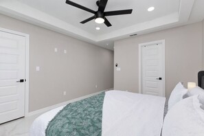 Een slaapkamer met een bed, een plafondventilator en twee witte deuren.