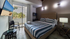 A hotel room with a bed, a TV, a chair, a table, and a nightstand.