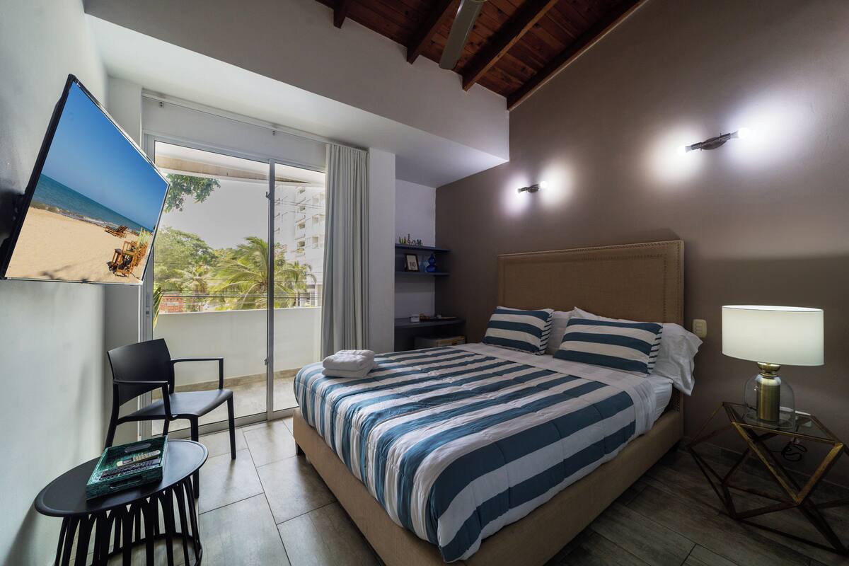 A hotel room with a bed, a TV, a chair, a table, and a nightstand.