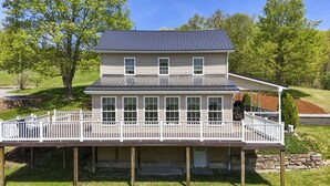 Une maison à deux étages, dotée d’un porche couvert et de fondations en pierre.