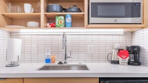 A modern kitchen with a stainless steel sink, a microwave, and a coffee maker. - Top of the Hill-Condotel on First Hill-Swedish (Seattle)