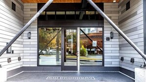 A building entrance with a modern design, featuring a glass door and a metal frame structure above. - Top of the Hill-Condotel on First Hill-Swedish (Seattle)