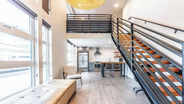 Un interior moderno con una escalera, un comedor y una zona de estar con vistas.