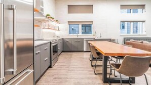 A modern kitchen with stainless steel appliances, a dining area with a wooden table and chairs, and a built-in oven. - Broadway-Condotel on First Hill (Seattle)