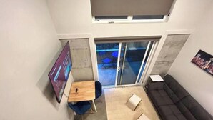Moderni sisustus, jossa on musta sohva, puinen pöytä ja televisio.
