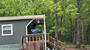 Une cabane avec une véranda, un foyer et un banc.