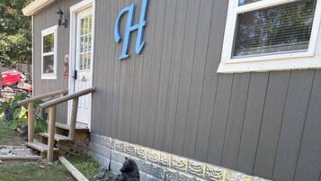 A building with a large 'H' on the side, a wooden staircase, and a garden area with a hose and a statue.