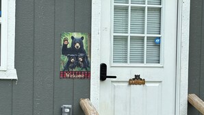 Une porte d’entrée avec une pancarte « Bienvenue », une boîte aux lettres et une rambarde en bois.