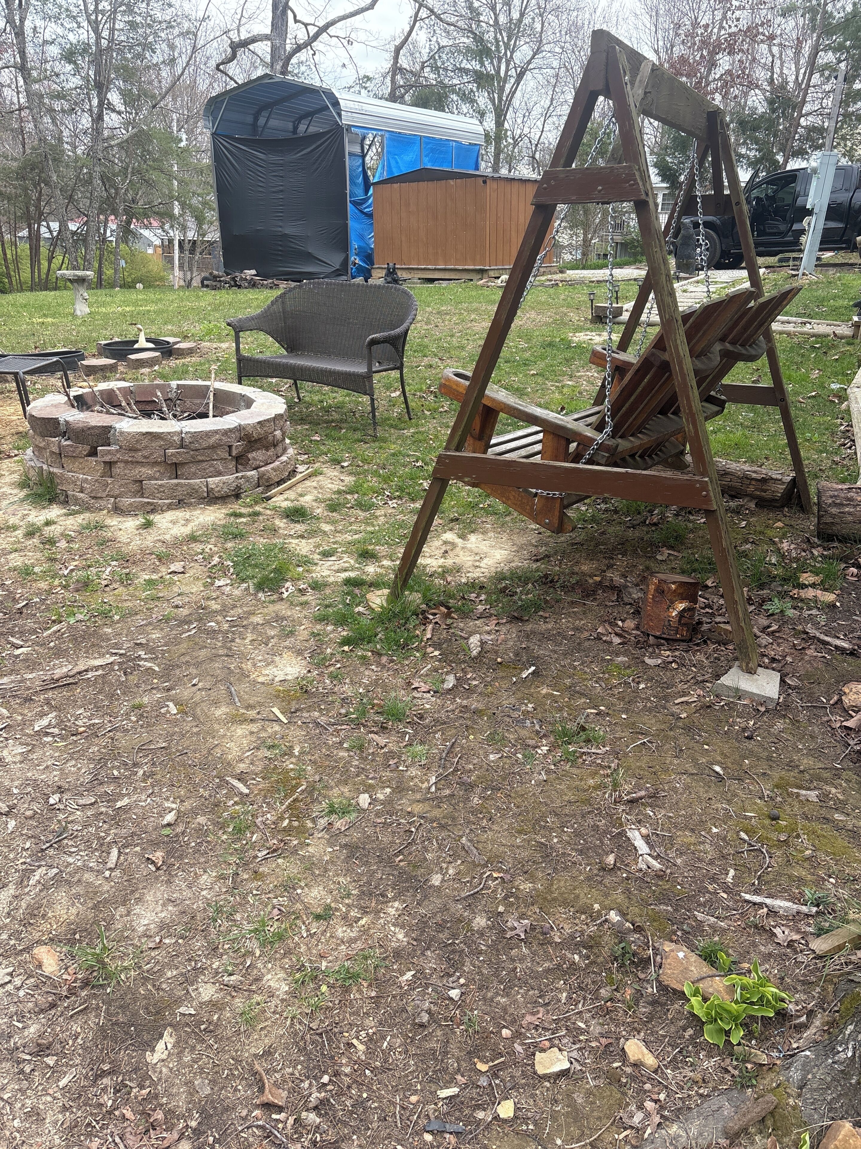 Un jardin avec un foyer, une balançoire et une structure abritée.