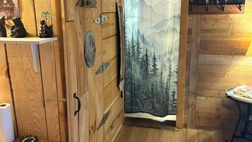 A wooden cabin interior with a cabin sign, a mountain-themed curtain, and a bear decoration on the wall.