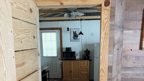 Un intérieur en bois avec un coin cuisine comprenant un four à micro-ondes, une machine à café et un luminaire suspendu.