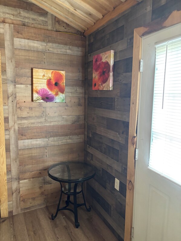A corner room with wooden panel walls, a round table, and two paintings.