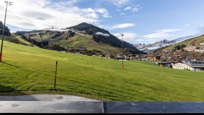 Et panorama over en by beliggende i en dal med grønne marker og bjerge i baggrunden.