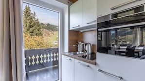 A modern kitchen with white cabinets, a stainless steel sink, and a view of a balcony with a railing.