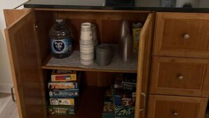 Une petite cuisine équipée d’une machine à café, d’un distributeur d’eau et de placards de rangement.