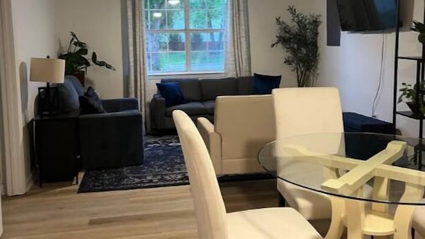 Un salon moderne avec une table à manger en verre, un canapé et un ventilateur de plafond.