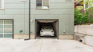 A car parked inside a garage with a concrete floor and a green exterior wall. - Alki Home w Parking, Fast WiFi, Steps to the Beach (Seattle)