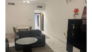 Una sala de estar con un sofá, una mesa redonda y un mueble para televisor.
