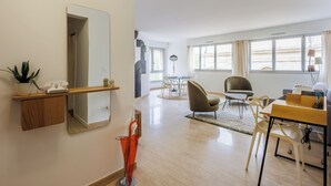A modern living room with a dining area, a large mirror, and a potted plant. - Appartement Limas - Welkeys (Avignon)