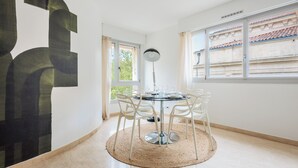 A dining area with a round table, white chairs, and a woven rug. - Appartement Limas - Welkeys (Avignon)
