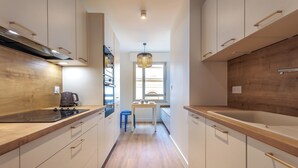 A modern kitchen with wooden countertops, white cabinets, and a central island with seating. - Appartement Limas - Welkeys (Avignon)