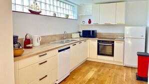 A modern kitchen with white cabinets, a wooden countertop, a sink, a microwave, an oven, and a refrigerator.