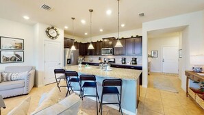 A modern kitchen with dark cabinets, a granite island, and pendant lighting. - Spacious 5-bedroom townhome with WiFi, AC in delightful Davenport (Davenport)