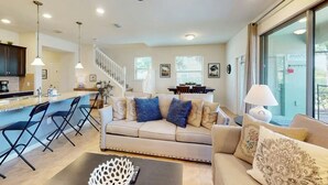 A modern living room with a sofa, coffee table, and a dining area with a staircase. - Spacious 5-bedroom townhome with WiFi, AC in delightful Davenport (Davenport)
