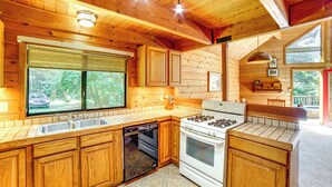 A kitchen with wooden cabinets, a stove, and a dishwasher. - Hot Tub, 1 Mi to Beach: 12-Acre Fort Bragg Cabin! (Fort Bragg)