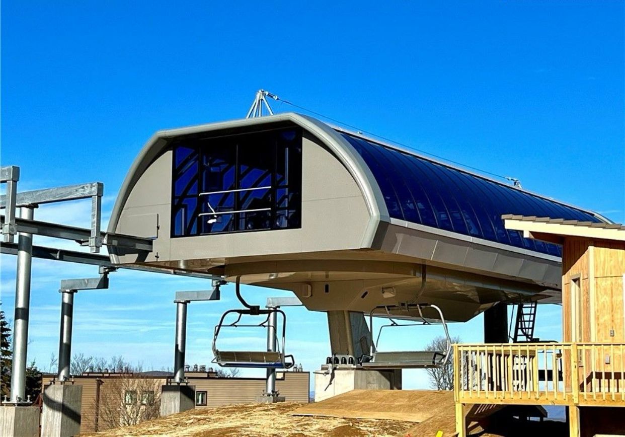 Une structure de télésiège dotée d’une zone d’attente abritée et d’une cabine en bois.