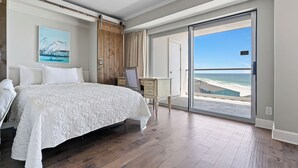 Un dormitorio con una cama grande, un escritorio y vista al mar.