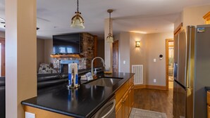 A modern kitchen with a black countertop, stainless steel appliances, and a stone accent wall. - Mayway Retreat - Echota Club Amenities, Beautiful Mountain Views (Banner Elk)