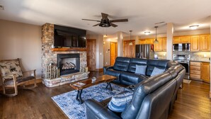 A modern living room with a stone fireplace, leather sofa, and a flat-screen TV. - Mayway Retreat - Echota Club Amenities, Beautiful Mountain Views (Banner Elk)