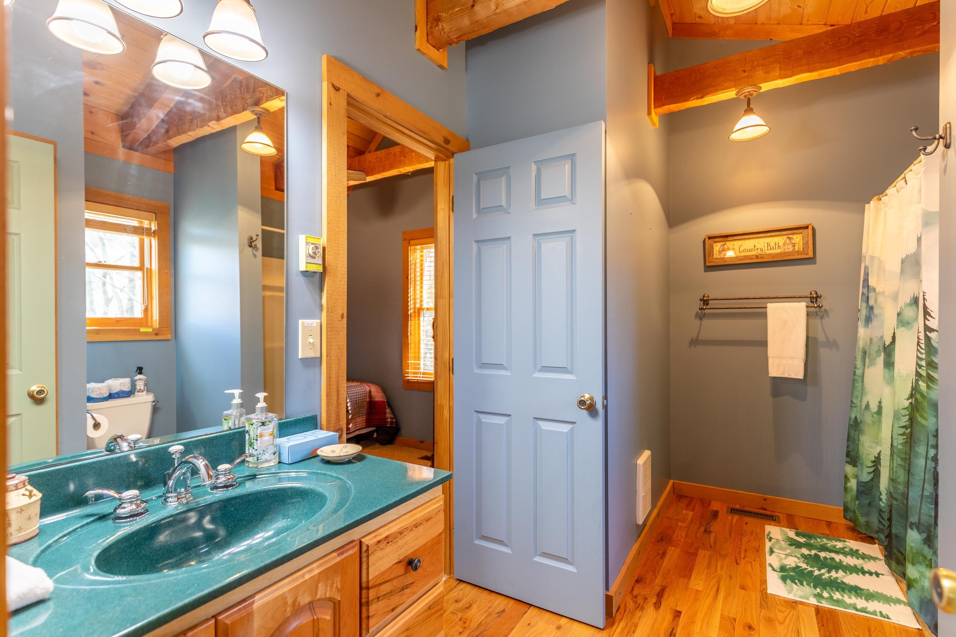 A cheerful country bath with warm wood accents and mountain-themed touches, ready to refresh after a day on the ridge.