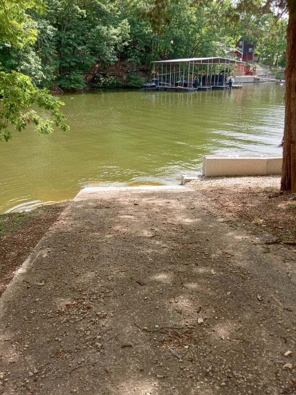 A riverside walkway with a covered seating area and a bridge in the background.